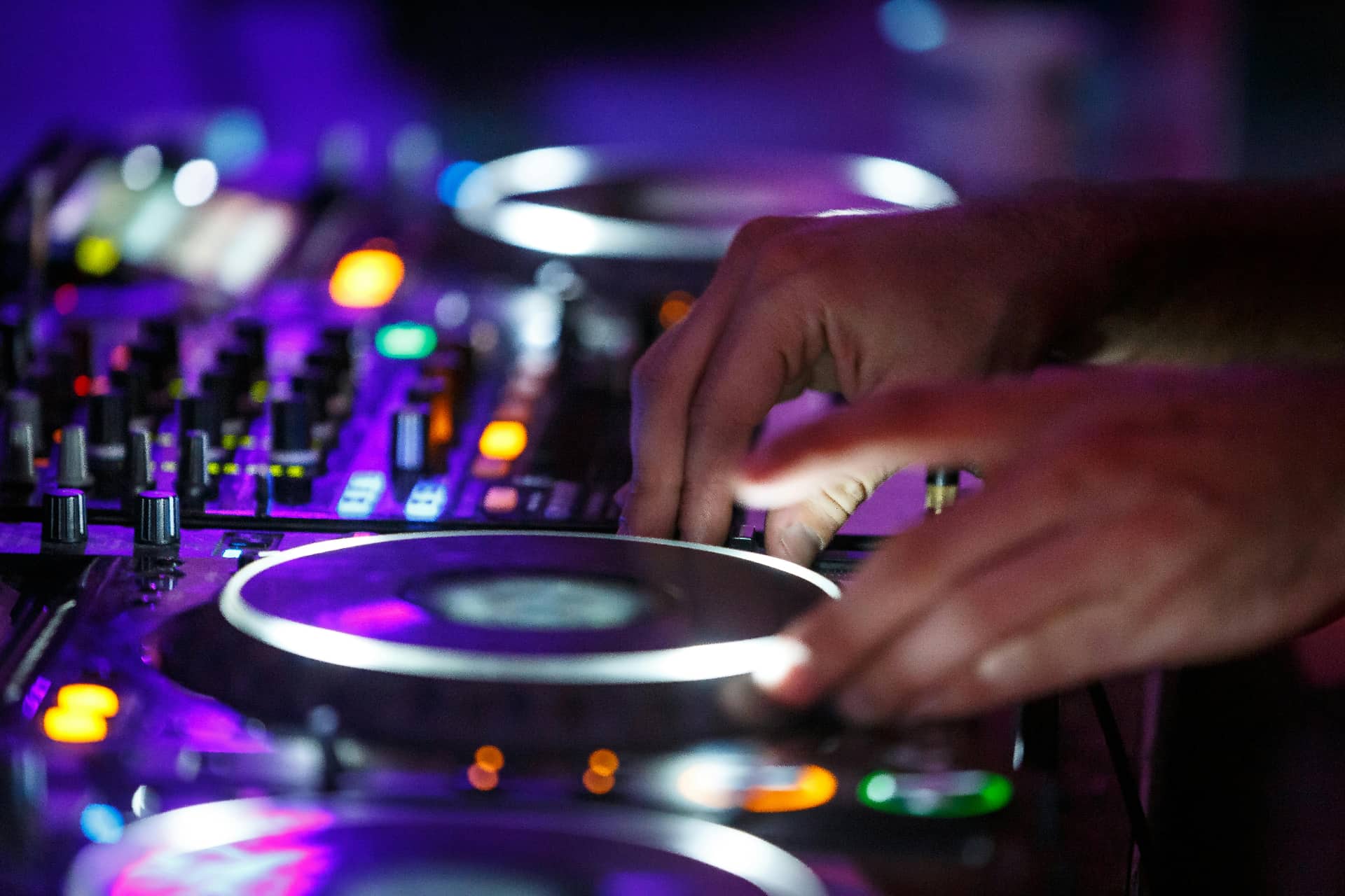 DJ performing at a live event with colorful lighting